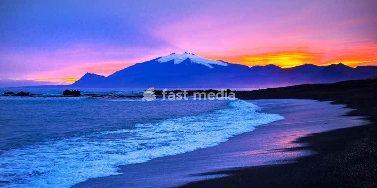 Strand mit Meeresbrandung und dem Snæfellsjoekull mit farbintensivem Sonnenuntergang hinter dem Gletscher, Langaholt, Snæfellsnes, Island, Europa