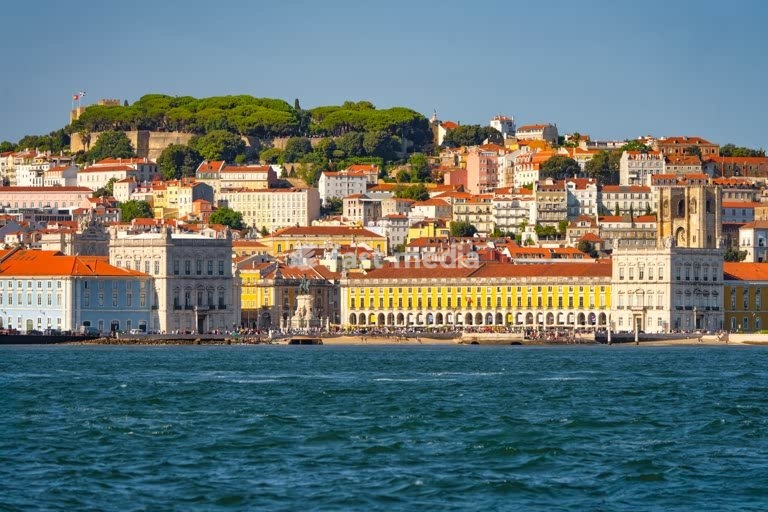 Lisbon cityscape with Praça do Comércio, Tagus River, Sé Cathedral and São Jorge Castle on the hillside, showcasing colorful historic architecture