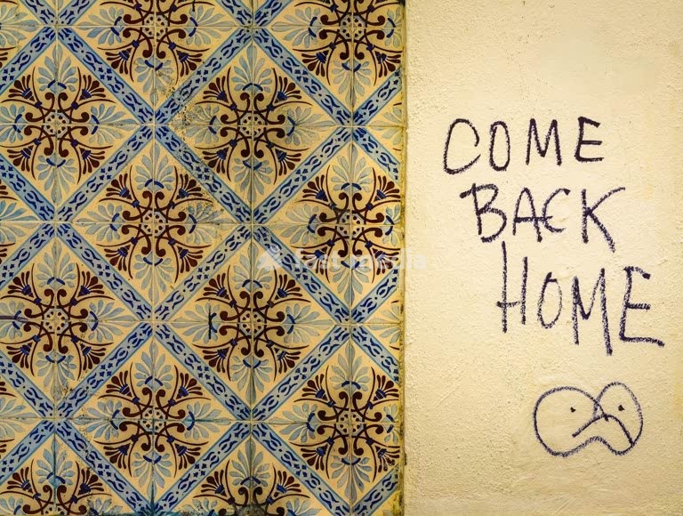 Lisbon, Portugal – traditional azulejo wall with handwritten graffiti message “Come Back Home”