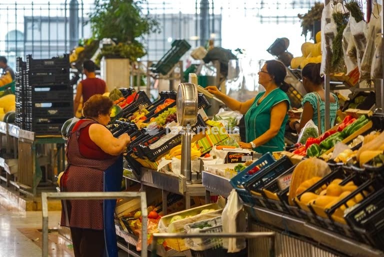 Geschäftige Verkäufer und Käufer an Gemüseständen in der Time Out Market Halle in Lissabon, Portugal