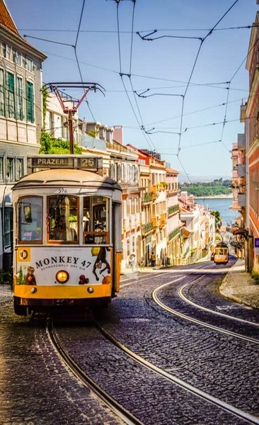 Lissabon, Portugal – historische gelbe Straßenbahn auf Kopfsteinpflaster im Morgensonnenlicht