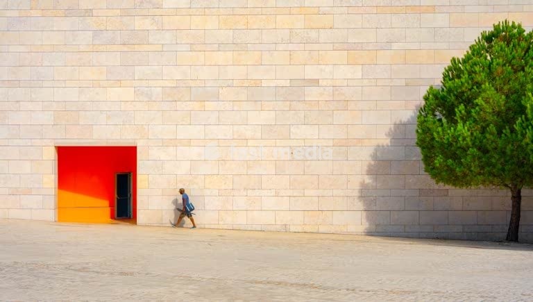 Lisbon, Portugal – Fisherman walking past red entrance at Champalimaud Foundation