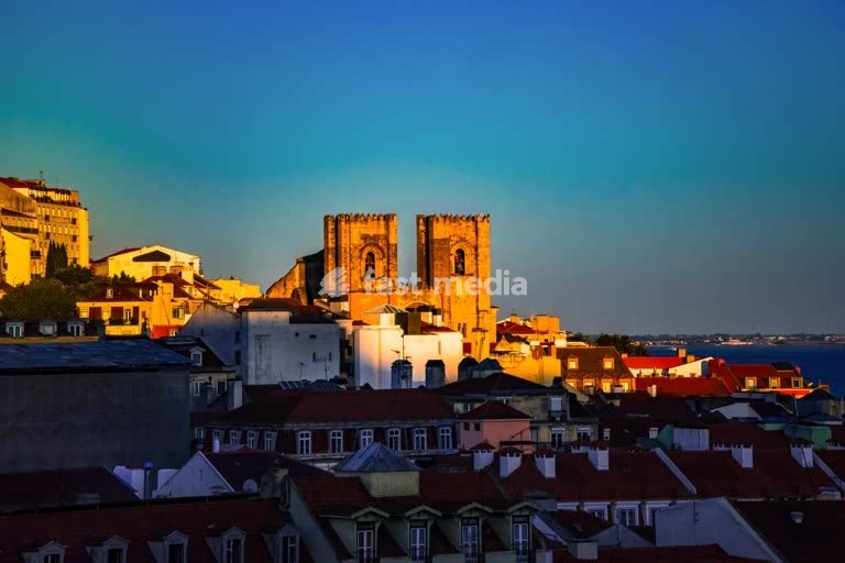 Last sunlight touches Lisbon’s cathedral Sé and houses in the Alfama district by the Tagus river