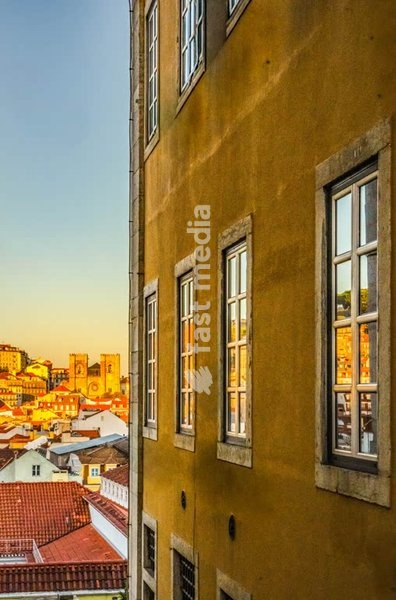 Lisbon, Portugal. Sunset light on historic facade with reflections over Alfama rooftops and cathedral Sé