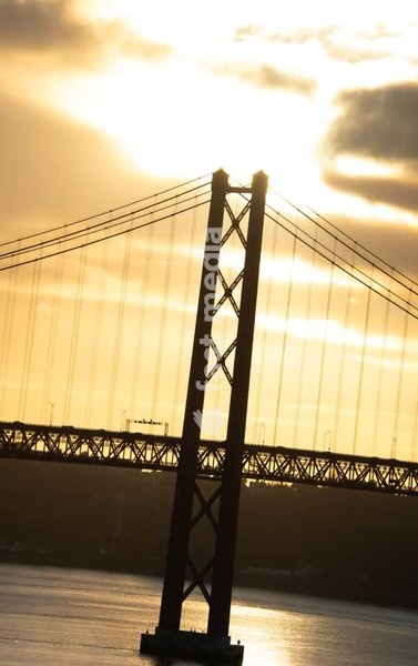 Lisbon, Portugal – Sunlit tower of Ponte 25 de Abril glowing above the Tagus River at sunset