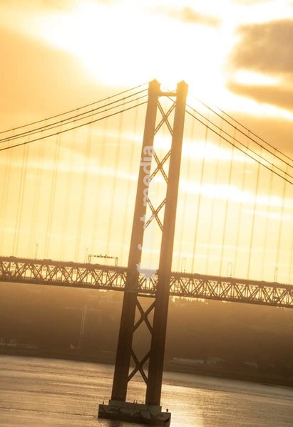 Lissabon, Portugal – Brückenturm der Ponte 25 de Abril im goldenen Morgenlicht über dem Tejo