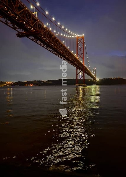 Bridge Ponte 25 de Abril illuminated at night with Cristo Rei statue, Lisbon, Portugal