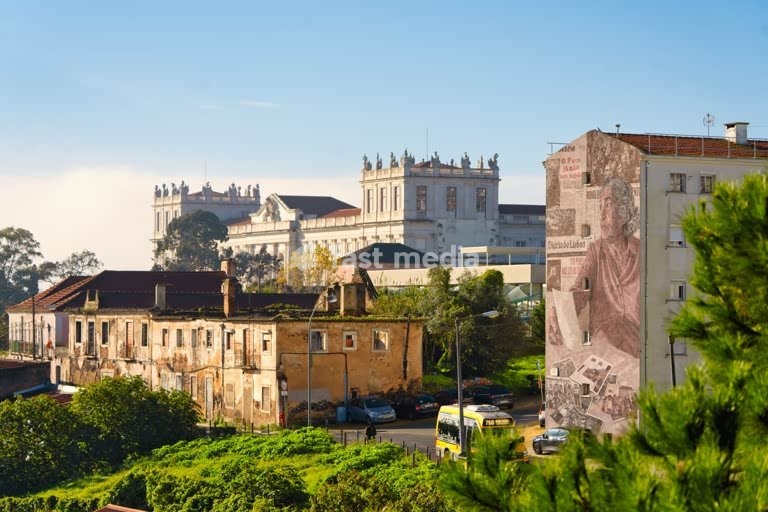 Ajuda Palace overlooks weathered rooftops and a colorful mural in Ajuda, Lisbon, Portugal