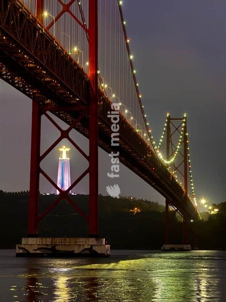 Bridge Ponte 25 de Abril illuminated at night with Cristo Rei statue, Lisbon, Portugal