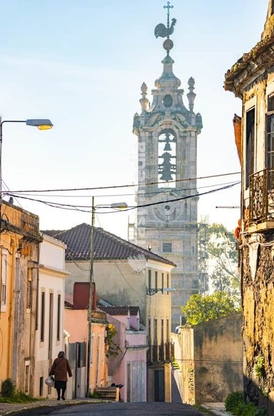Foggy early morning street in Ajuda, Lisbon, with Baroque Torre da Ajuda bell tower