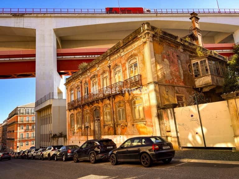 Faded 19th-century mansion beneath the Ponte 25 de Abril viaduct, Alcântara, Lisbon. Brutal urban planning