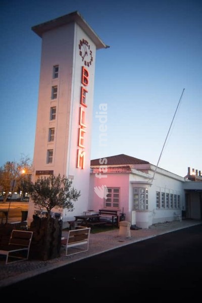 Art Deco Belém ferry terminal tower with clock and neon sign at dusk, Lisbon, Portugal