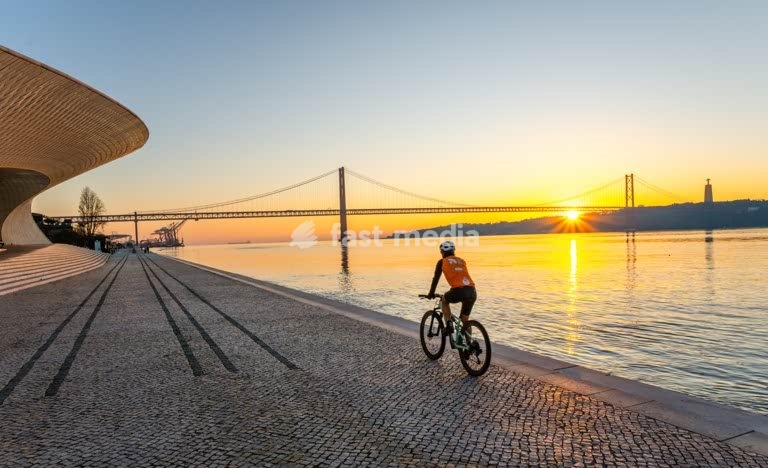 Cyclist silhouette at River Tagus, 25 de Abril Bridge sunrise Lisbon Portugal cool modern mood