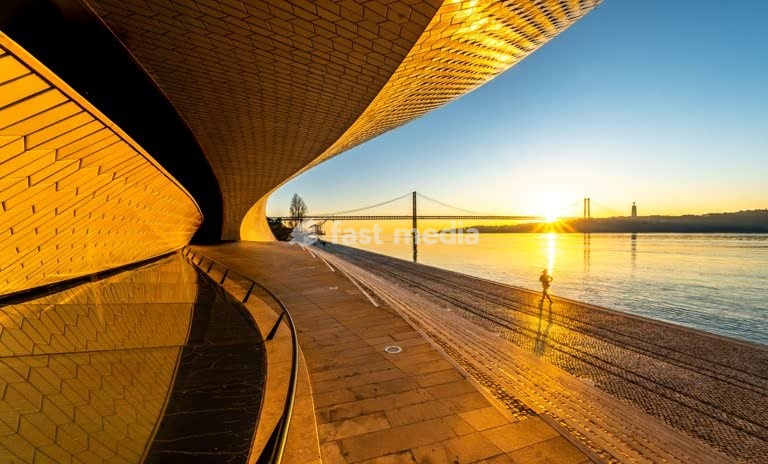 MAAT Museum curvilinear facade with jogger at sunrise, Tagus River Lisbon Portugal – contemporary architecture