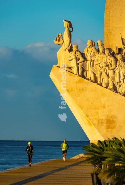 Joggers at the base of Padrão dos Descobrimentos monument at sunrise, Belém riverfront, Lisbon