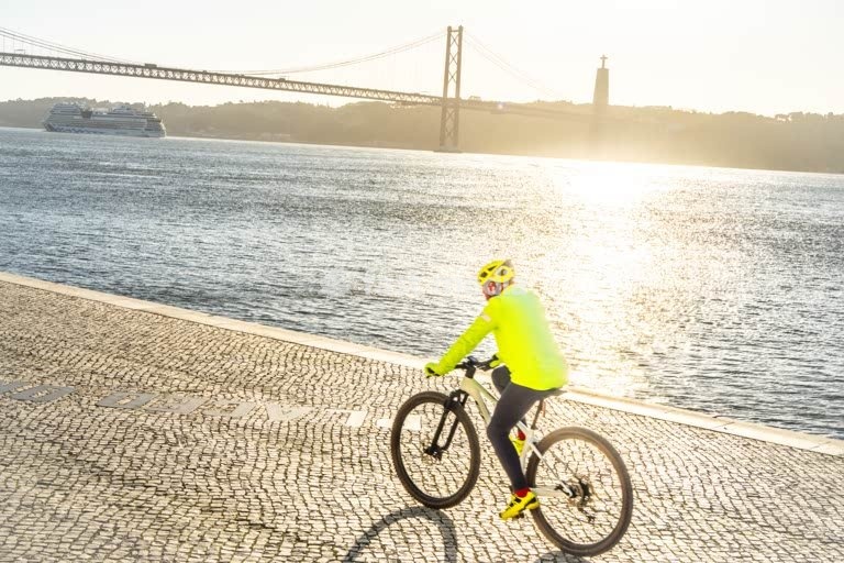 Cyclist silhouette at River Tagus, 25 de Abril Bridge sunrise Lisbon Portugal cool modern mood