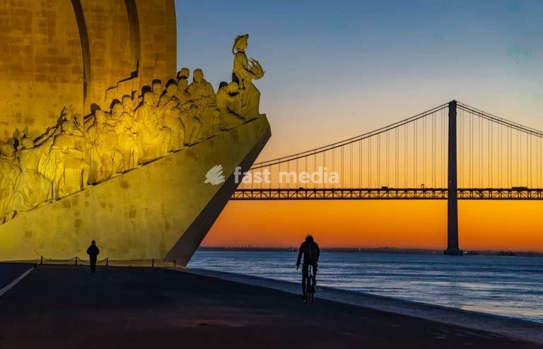 Jogger silhouette at Discovery Monument (Padrão dos Descobrimentos) and 25 de Abril Bridge, sunrise Lisbon Belem Portugal