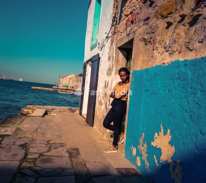 Secret Lisbon: Woman leaning in weathered blue doorway by the water, Cacilhas, Lisbon, mood shot
