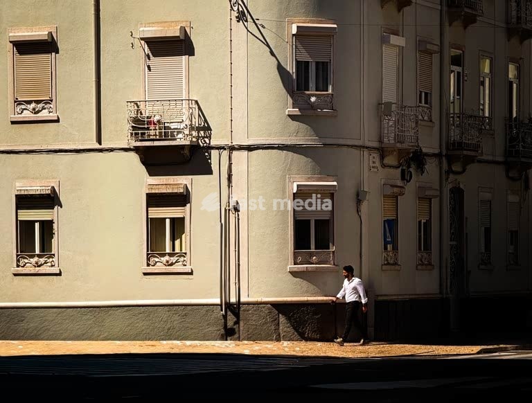 Man walking past green shuttered facade in evening light, Campo de Ourique, Lisbon