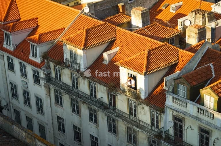 A couple standing on a balcony in Baixa district of Lisbon, Portugal