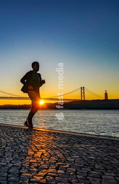 Lisboa, Portugal. Um corredor matinal à beira-rio do Tejo. A Ponte de 24 de Abril ao fundo