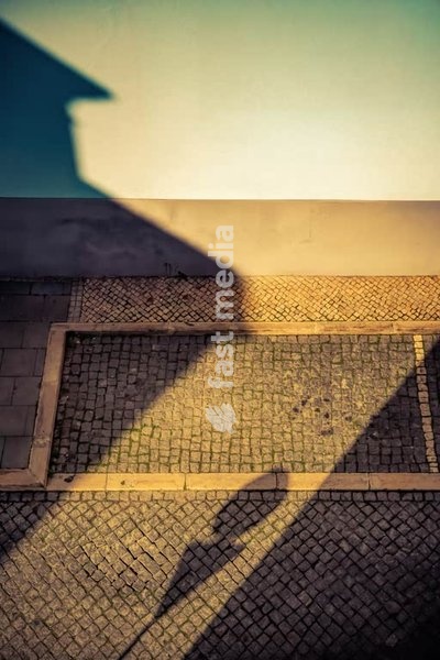 Shadow silhouette on cobblestones, moody modern street photography, Lisbon, Portugal