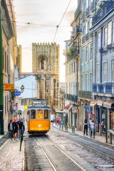 Iconic yellow tram in Lisbon, Portugal. Catherdal S´in the background