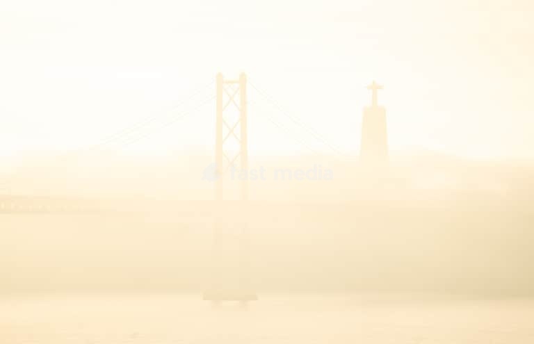 Ponte 25 de Abril suspension bridge silhouette in golden haze, Tagus River, Lisbon, Portugal