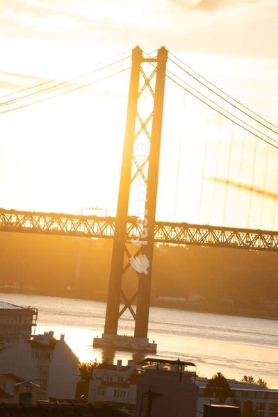 Ponte 25 de Abril suspension bridge silhouette in golden haze, Tagus River, Lisbon, Portugal