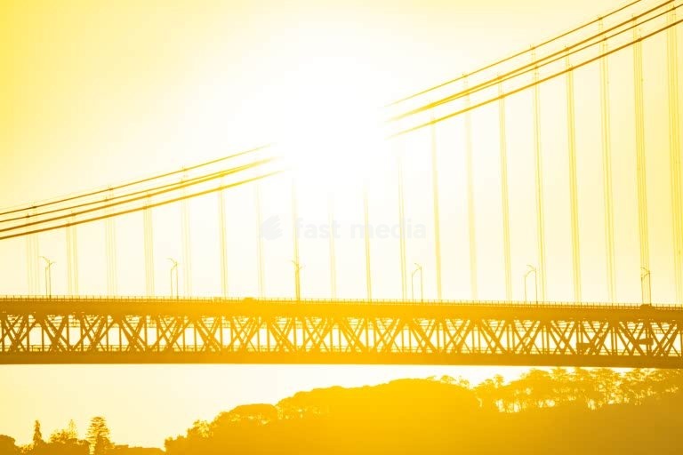 Ponte 25 de Abril suspension bridge silhouette in golden haze, Tagus River, Lisbon, Portugal