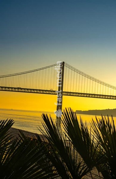 Ponte 25 de Abril suspension bridge silhouette in golden haze, Tagus River, Lisbon, Portugal