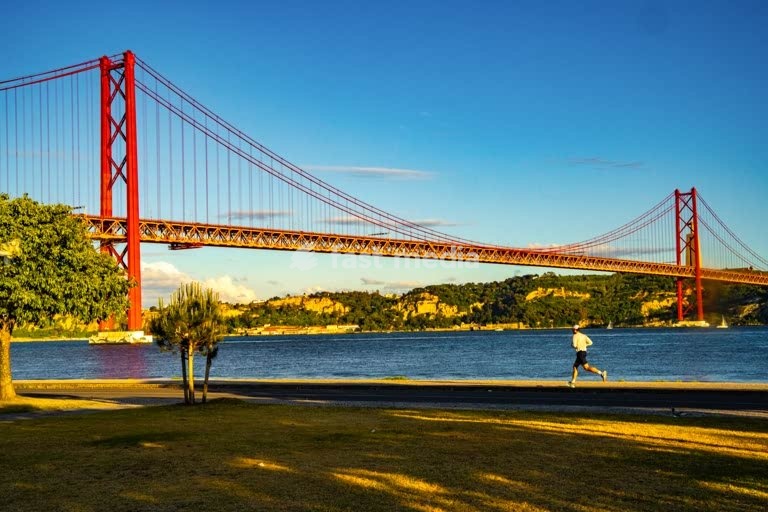 Um corredor perto da Ponte 25 de Abril sobre o rio Tejo em Belém, Lisboa, Portugal