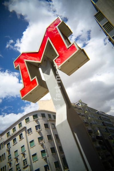 Lisbon Metro red M sign, low-angle, cloud, residential facade, Lisbon, Portugal