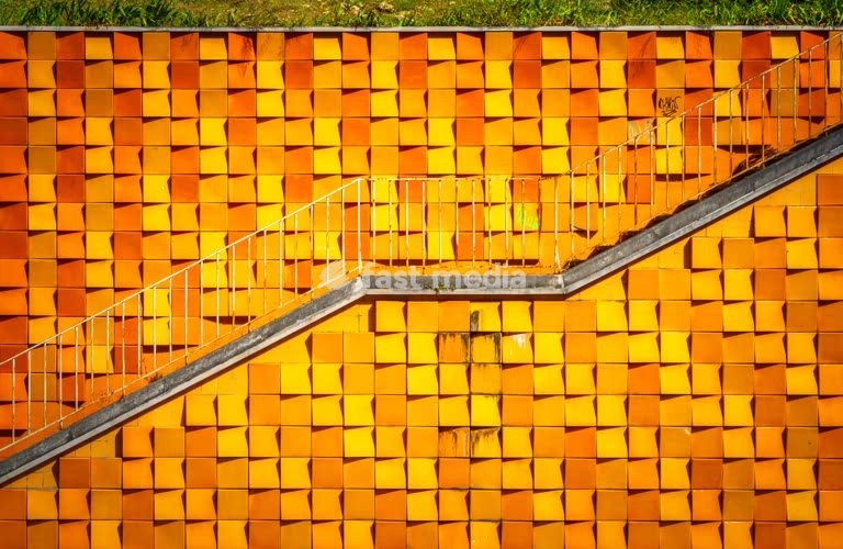Bold geometric orange ceramic tile wall with diagonal staircase, Avenida Infante Santo, Lisbon, Portugal