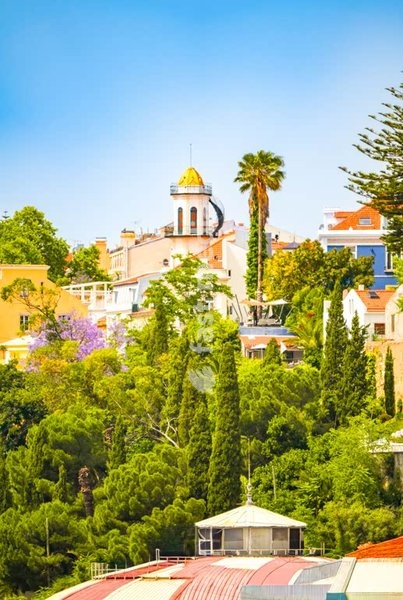 Lisbon skyline with ornate golden-domed Torel Palace tower rising above lush Mediterranean greenery, Portugal