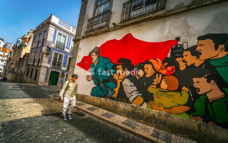 Carnation Revolution mural with pedestrian, Bairro Alto cobblestone street, Lisbon, Portugal