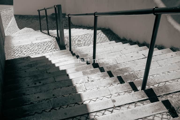 Sunlit stone staircase with sharp shadows and black railings, Belém, Lisbon, mood shot