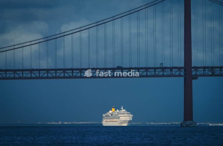Cruise ship under Ponte 25 de Abril, dramatic stormy sky, Tagus River, Lisbon, Portugal – moody photography