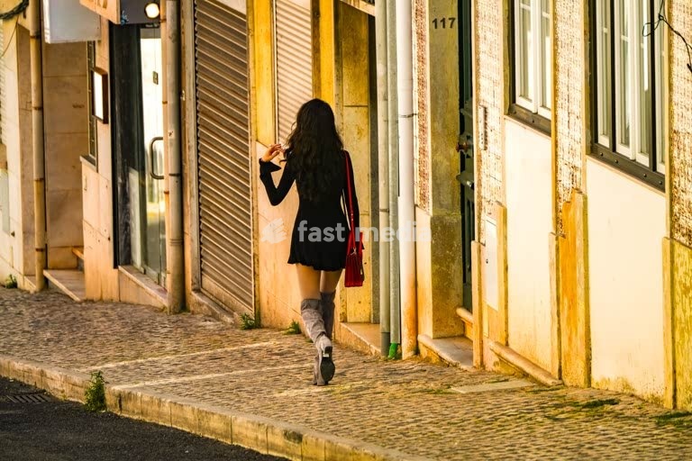 A beautiful young woman in boots walking downhil in the streets of Boa Hora, Lisbon, Portugal
