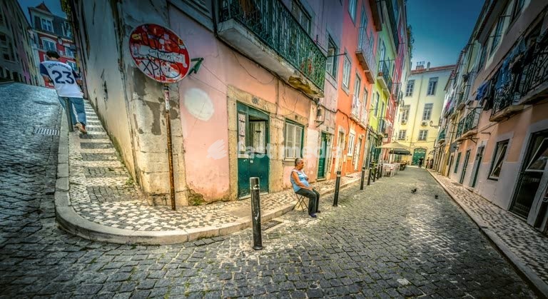 Old woman in front of her house in a colourful street in Bairro Alto, Lisbon, Portugal