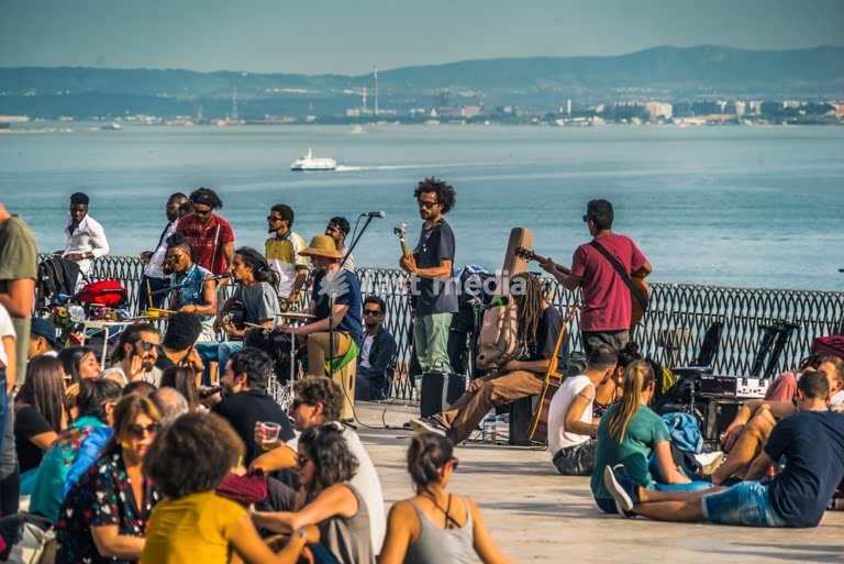 Street musicians perform for a crowd at Miradouro de Santa Catarina, Lisbon, Tagus River view