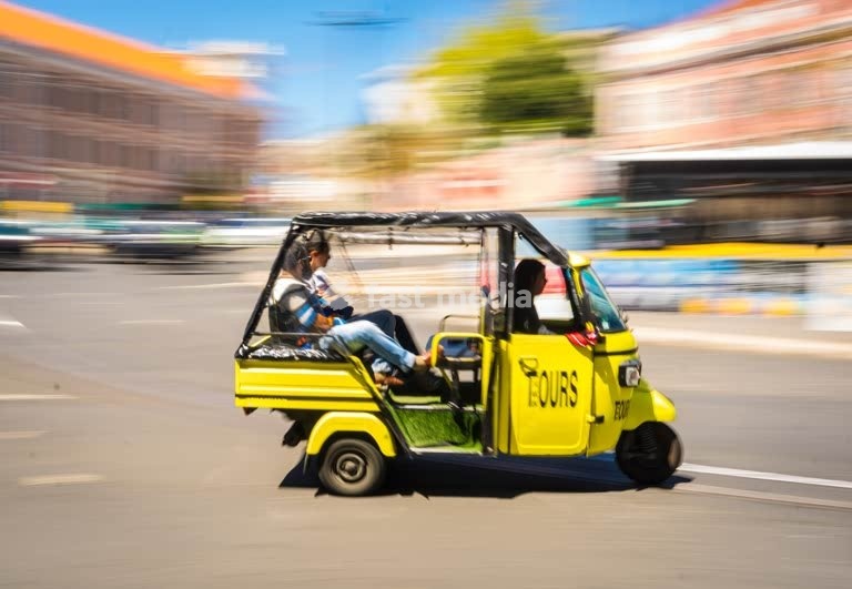 Yellow tuk-tuk in motion blur on a Lisbon street, Portugal, tourist tour vehicle in action