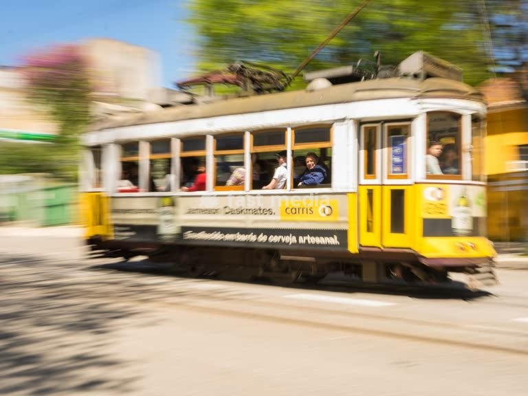Iconic yellow Tram 28 speeds through Lisbon in motion blur, Portugal