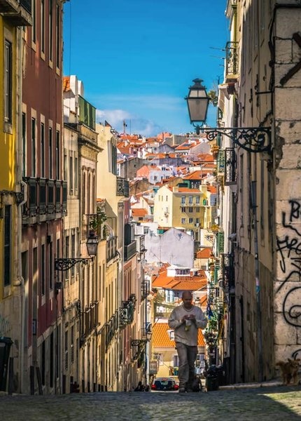 A man comes up a steep street, typical in Bairro Alto, Lisbon, Portugal