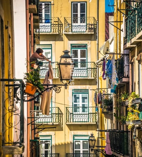 A Woman hangs her laundry out the window, Lisbon, Portugal, street in Bairro Alto district