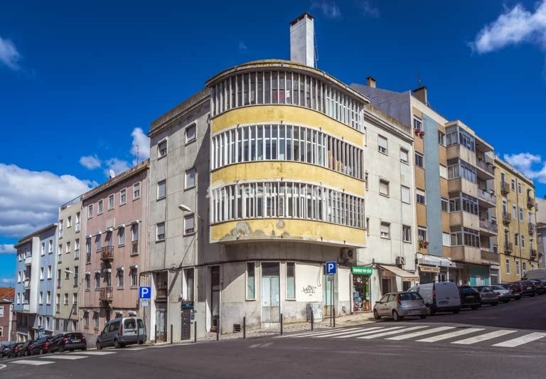MODERNIST CORNER BUILDING, curved balconies, weathered yellow facade, Campo de Ourique, Lisbon, Portugal