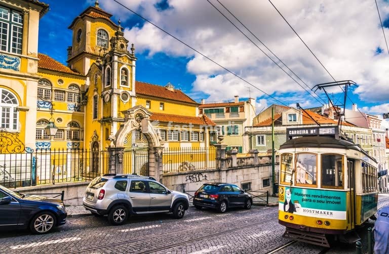 Yellow tram passes historic Lapa palace, Palacete dos Condes de Monte Real, Lisbon, Portugal streetscape