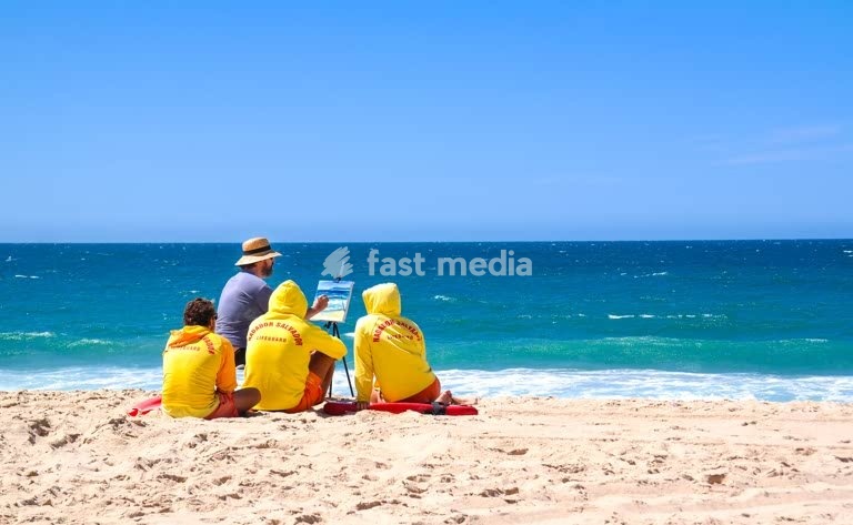 Lifeguards on Portugal's Atlantic coast watching an artist at work, a summer travel and seaside lifestyle scene