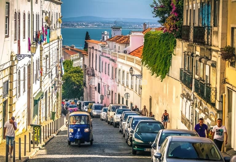 Lisbon. A tuk-tuk of the first generation climbing uphill in Graça