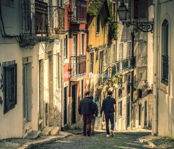 Three men going down a steep street in the Bairro Alto district of Lisbon, Portugal.
